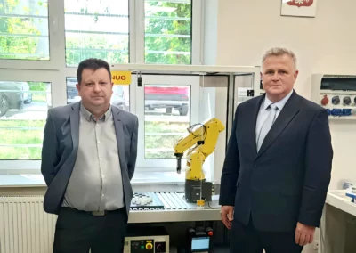 Dr Adam Duszyk i dyrektor Piotr Zarzyka w sali dydaktycznej z robotem przemysłowym FANUC podczas wydarzenia SkillsPoland 2025