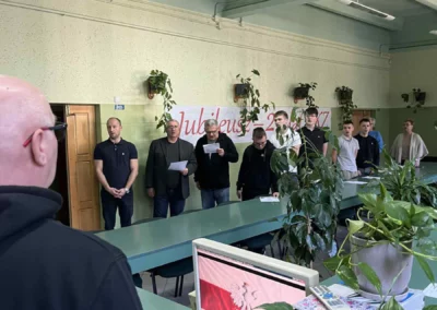 Komputer z flagą Polski i śpiewający uczniowie podczas akcji „Szkoła do hymnu”