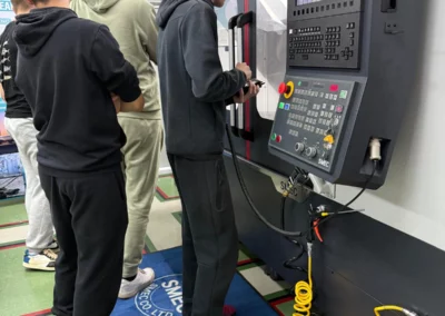 Uczniowie uczą się obsługi panelu frezarki CNC SMEC w nowoczesnej pracowni CKZiU2.