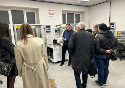 Dyrektor prezentuje działanie robota przemysłowego uczestnikom spotkania w Branżowym Centrum Umiejętności Nr 2