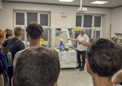 Uczniowie obserwują prezentację robota przemysłowego w pracowni automatyki CKZiU Nr 2 w Radomiu.